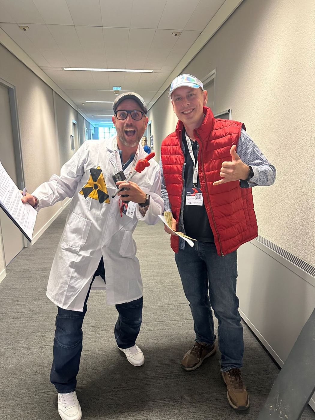 De twee facilitators verkleed als Doc Brown in witte labjas en Marty McFly in rode bodywarmer, lachend in de gang van het congresgebouw.